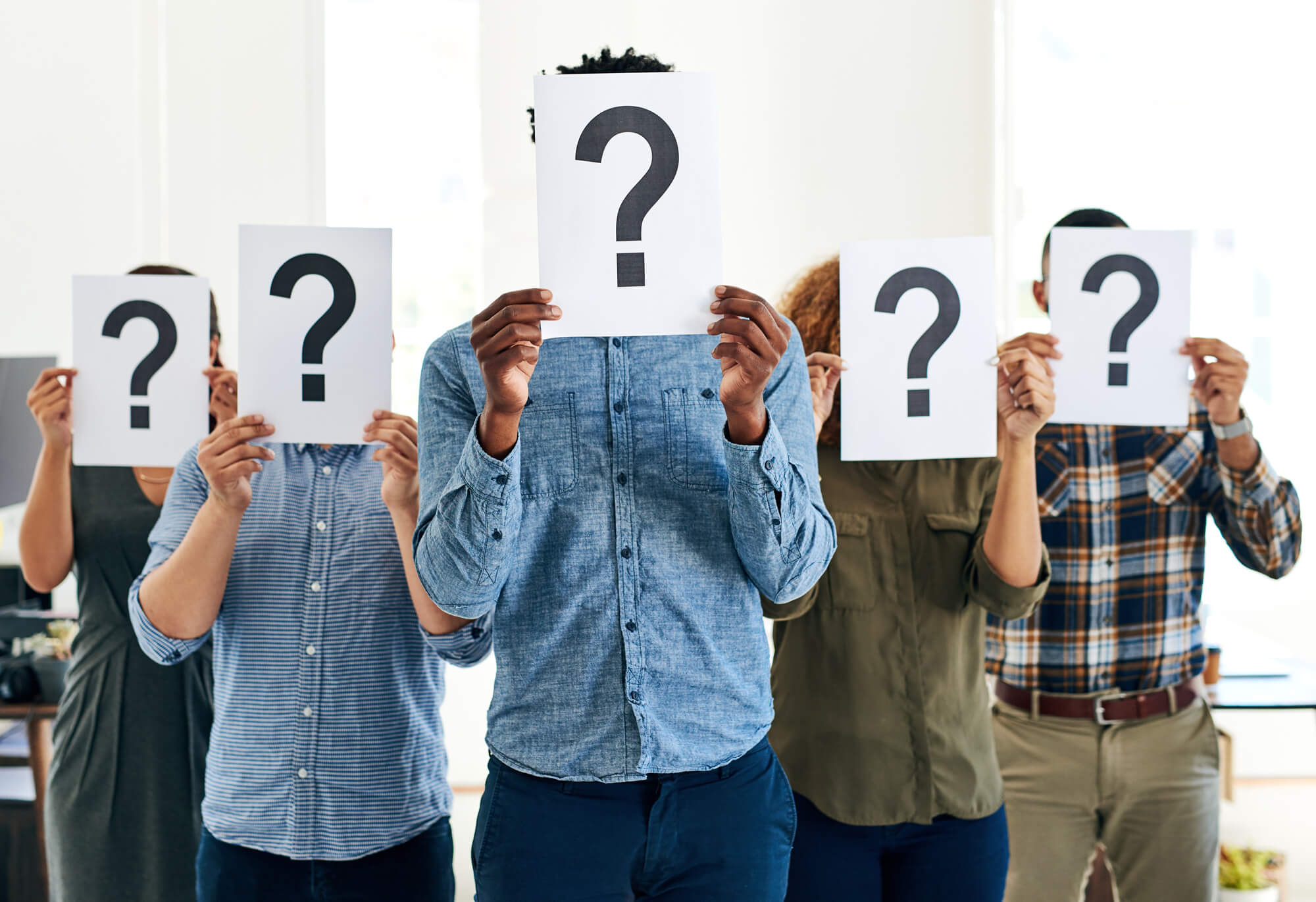 An image of-a group of businesspeople holding question mark signs